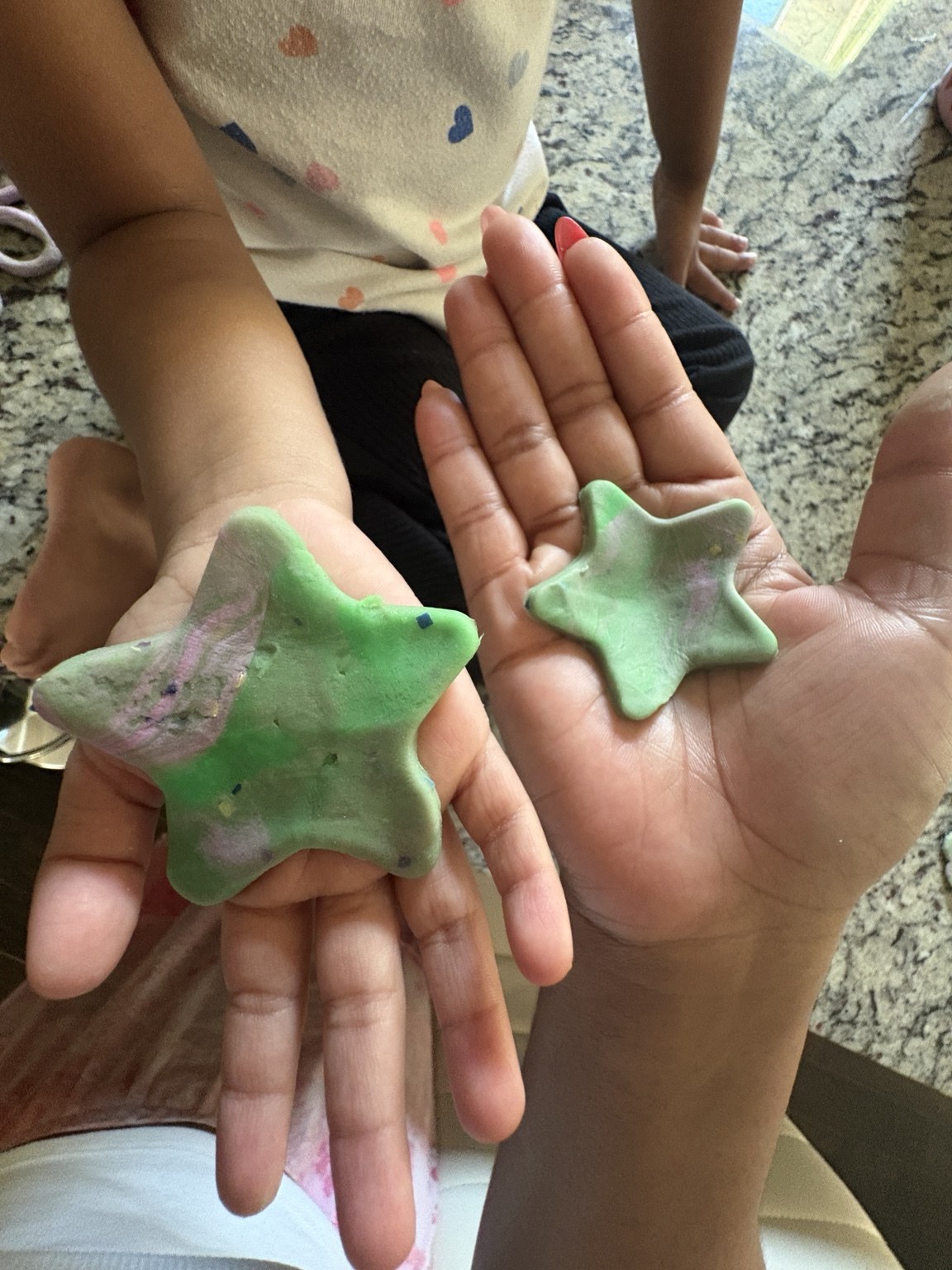 A child and an adult holding green star-shaped creations in their hands during a visit with friends in Georgia